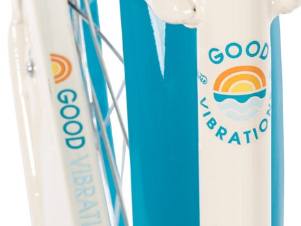 Close-up of the “Good Vibrations” logo on a cream and teal bike frame, showcasing retro-inspired design details.