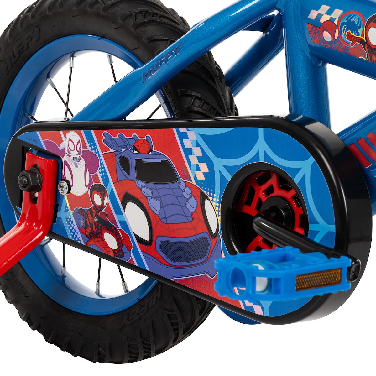 Close-up of a kids’ bike drivetrain with a full-color Spidey-themed chain guard and red-and-blue pedal. Close-up of a kids’ bike drivetrain with a full-color Spidey-themed chain guard and red-and-blue pedal.