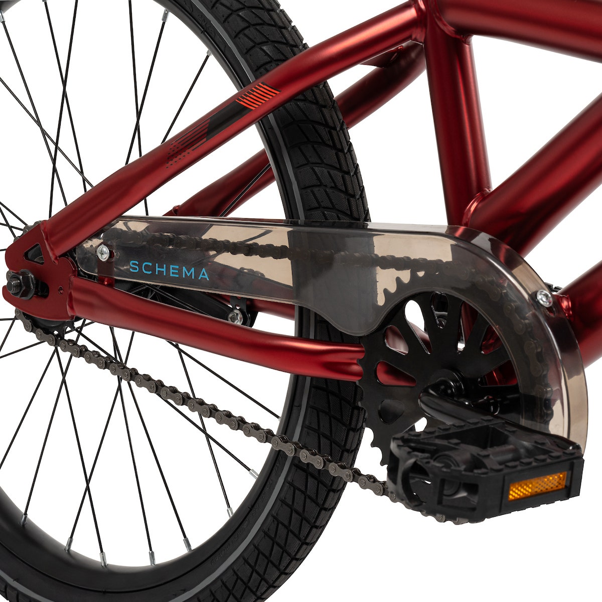 Side view of a BMX bike drivetrain with a black pedal and translucent chain guard on a red frame. Side view of a BMX bike drivetrain with a black pedal and translucent chain guard on a red frame.