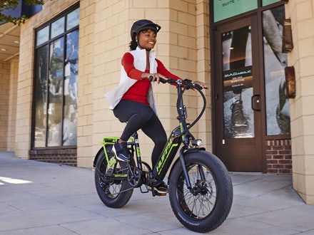 Woman riding a Huffy Motoric electric bike with fat tires, showcasing urban commuting versatility and comfort. Woman riding a Huffy Motoric electric bike with fat tires, showcasing urban commuting versatility and comfort.